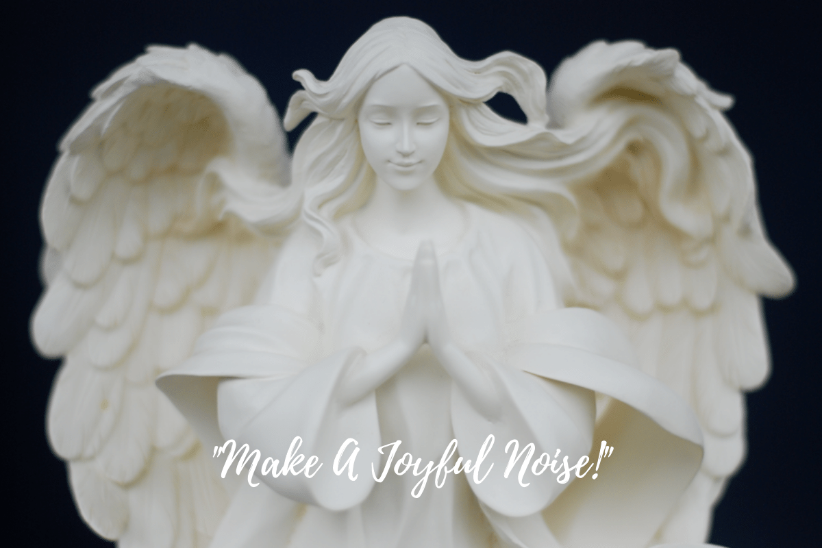 An alabaster angel with her wings spread out, hair flowing, and hands folded in prayer.